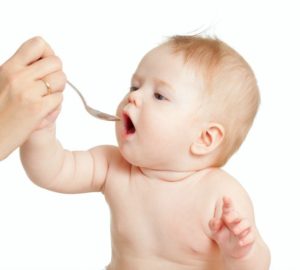 Младенец ест лекарство с ложки