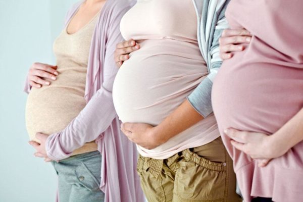 Беременные женщины держатся за животы